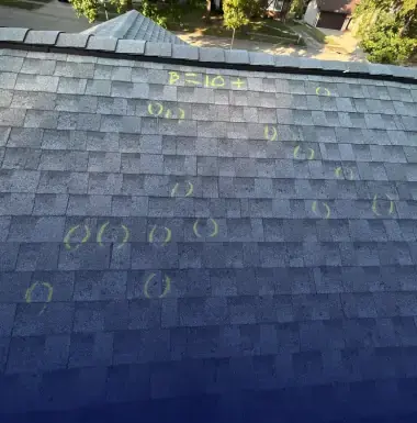 Close-up of hail damage marks chalked on asphalt shingles for an insurance inspection in St. Louis Metro area